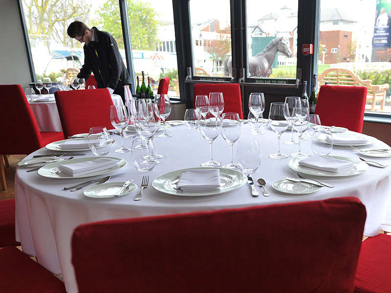 Red banqueting chairs with white tableware on round tables